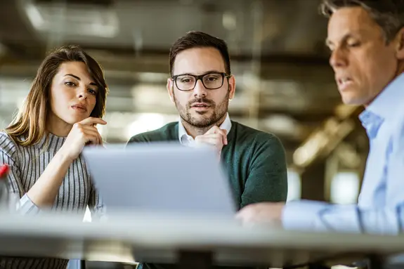 Young couple and real estate agent using laptop in a meeting
