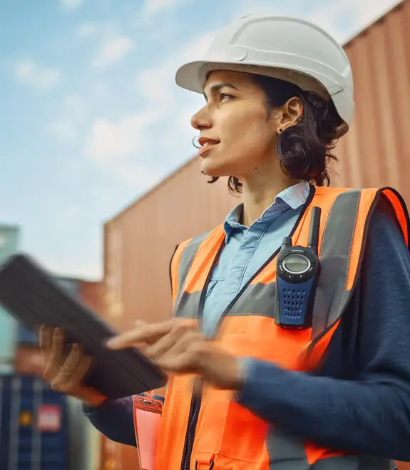 Woman on export site with helmet, tablet and an orange vest